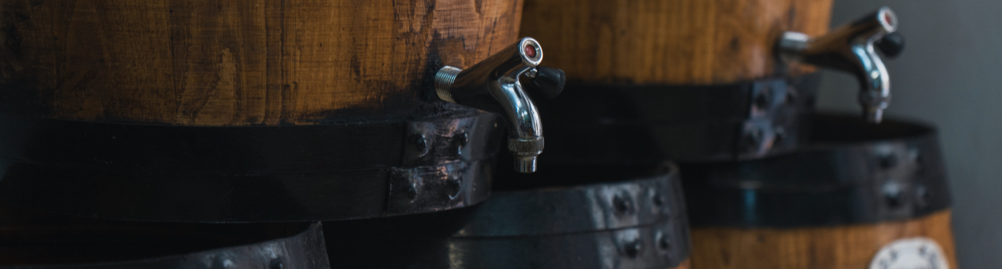 Botes de fusta envellida amb grifons cromats alineades en un interior amb llum tènue.